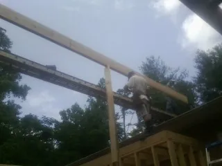 Carpenter setting a ridge beam over a new addition frame — Ice Dam Removal by Roofing Brothers in Blakely