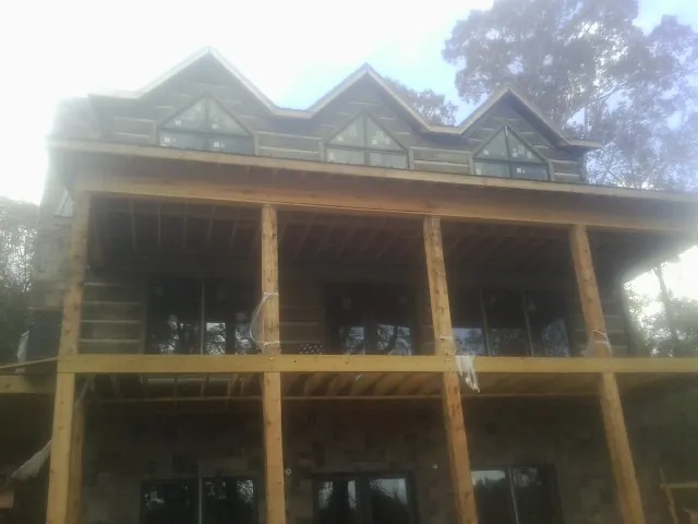 Dormers and porch framing on a large log home under construction — Roof Coating work by our crew in Blakely