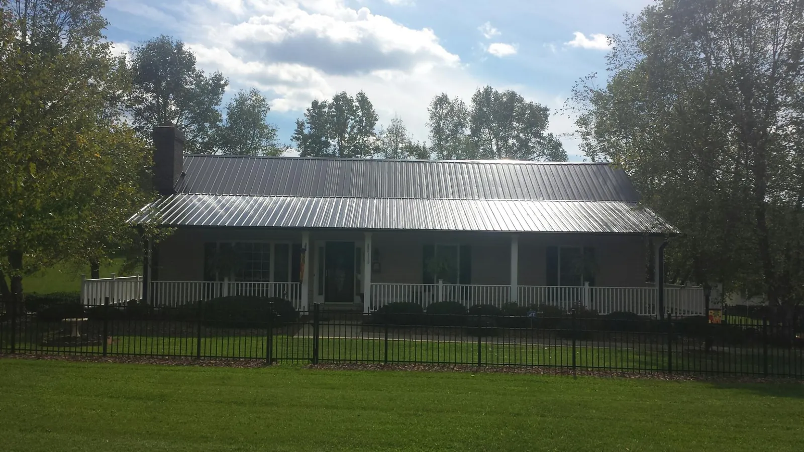 Gray metal roof on a brick ranch with a full width front porch — Gutter Guard Installation work by our crew in Blakely