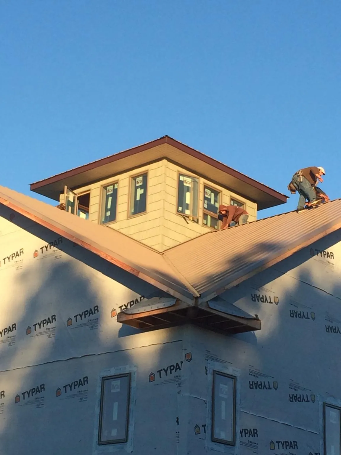Roofers working around a rooftop cupola on a new metal roof at sunset — Roof Waterproofing in Blakely by Roofing Brothers